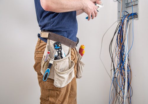electrician-builder-work-examines-cable-connection-electrical-line-fuselage-industrial-switchboard-professional-overalls-with-electrician-s-tool